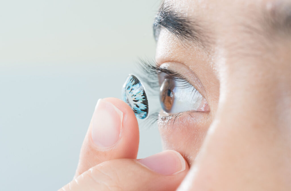 Young woman putting colored contact lenses into her eye