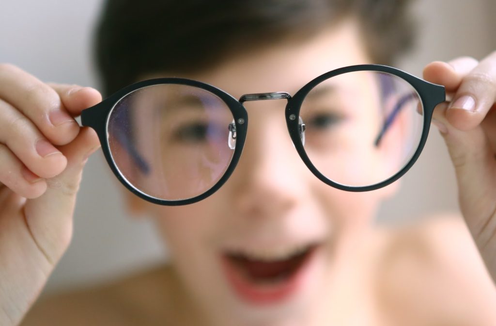 Young happy boy holding glasses close to camera
