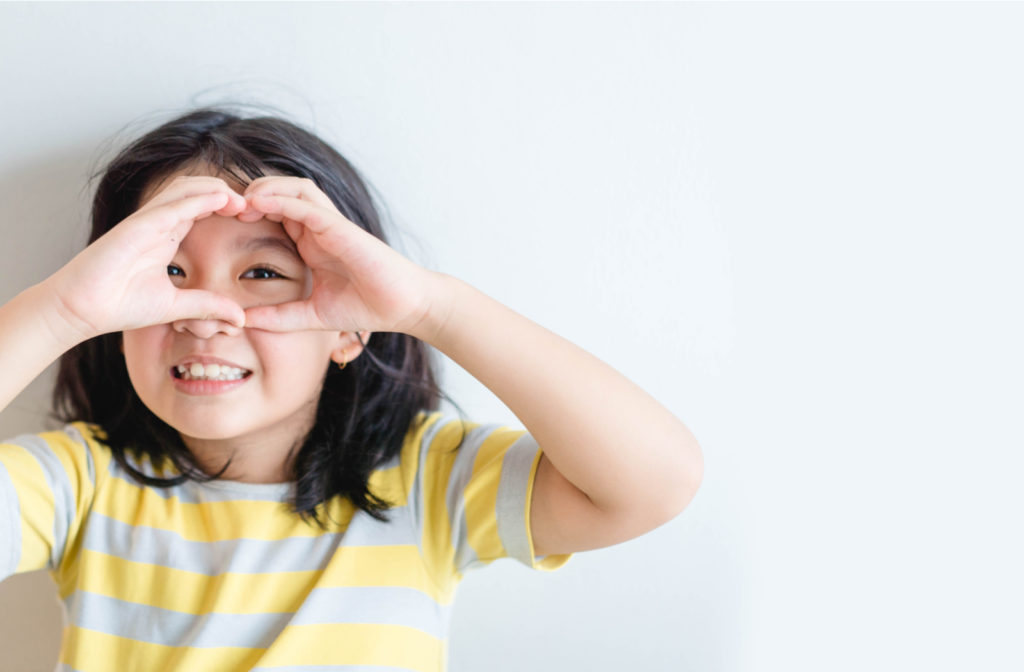 Young child creating circle around eye portraying healthy vision