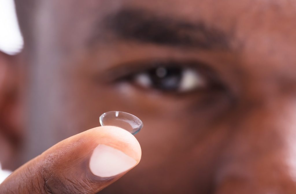 Man putting in contact lens with camera focused on lens and finger