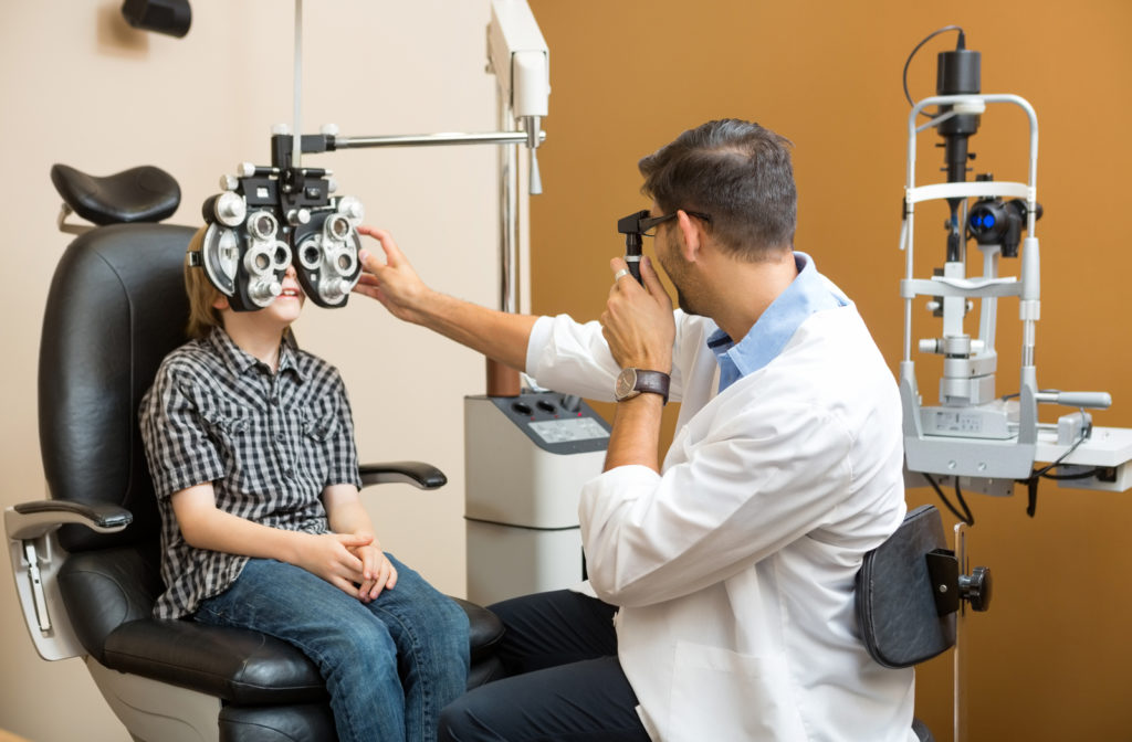Young boy undergoing eye exam by optometrist in clinic