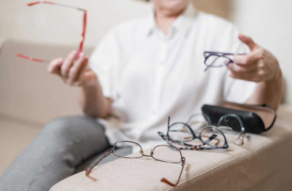 Woman choosing a pair of glasses in her collection that fits her best.