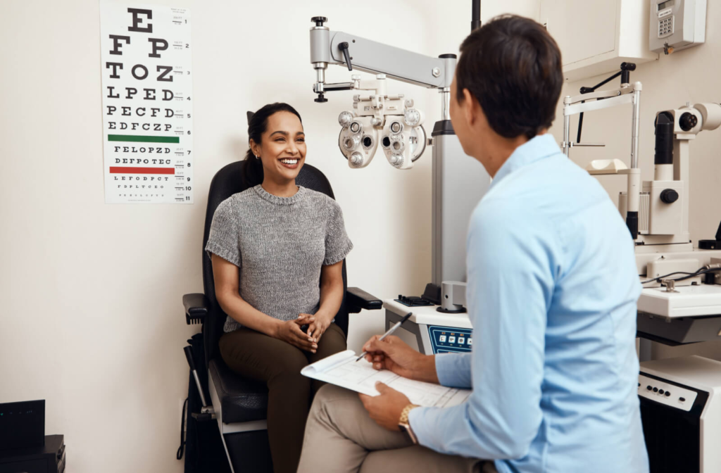 A male optometrist is writing a prescription after he conducted an eye exam on her patient.