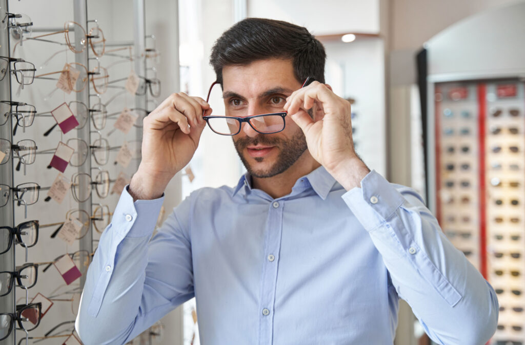 A professional-looking man trying on a pair of glasses in an optical store.