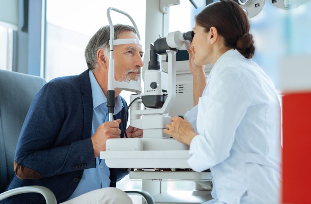 A man looks intently into an optometry machine while an optometrist examines his eyes for diabetic retinopathy.