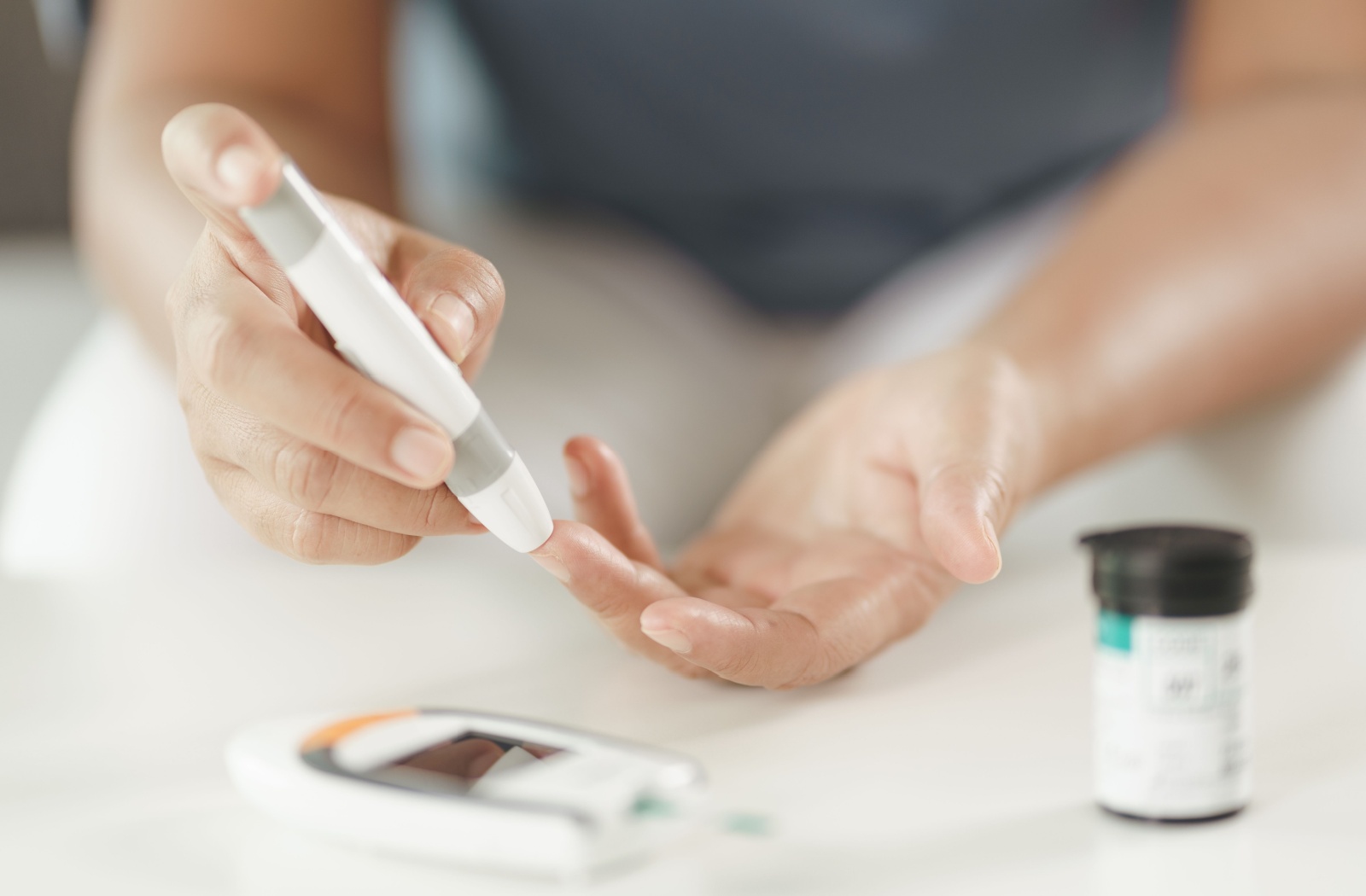 A pair of hands uses a lancet to check blood sugar levels for diabetes treatment which can help with diabetic retinopathy.