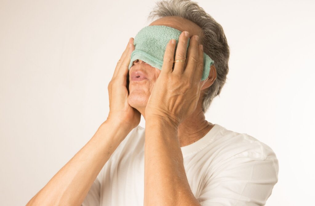 An older adult uses a warm compress mask to unclog meibomian glands.