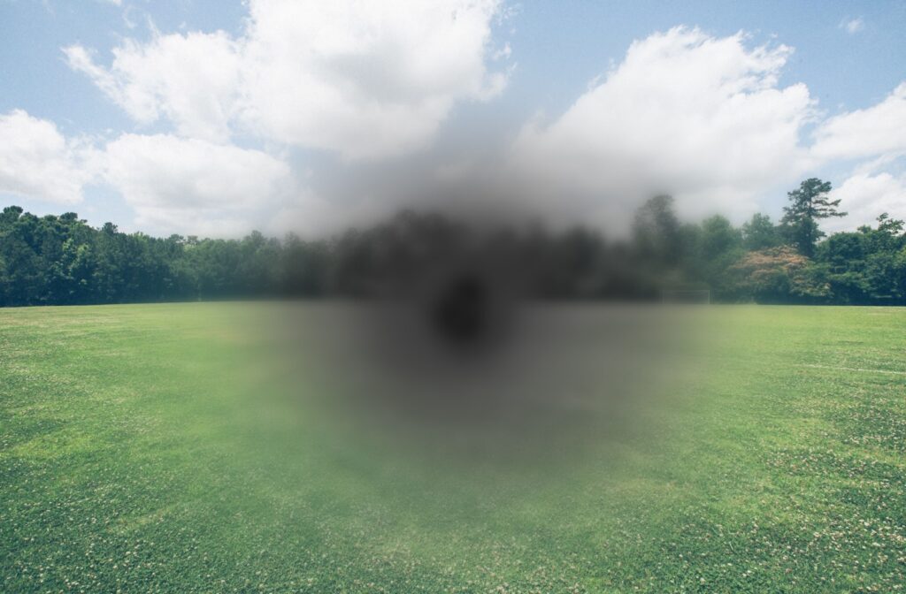 A simulation of macular degeneration—a green field appears blurred and greyscale in the center.