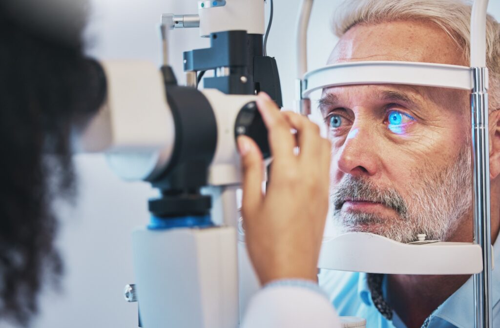 A person with light-blue eyes sits in an optometrists office while their optometrist examines their eyes.