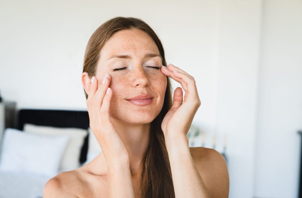 a person with their eyes closed and hands touching the skin around their eyes
