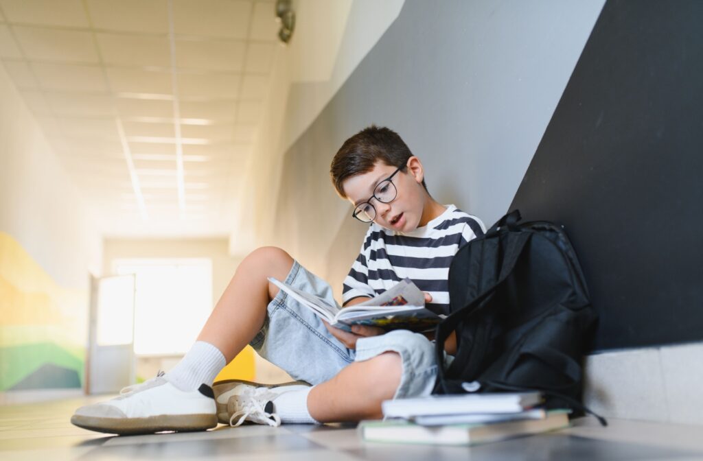 A young child wearing myopia control glasses while reading a book at school