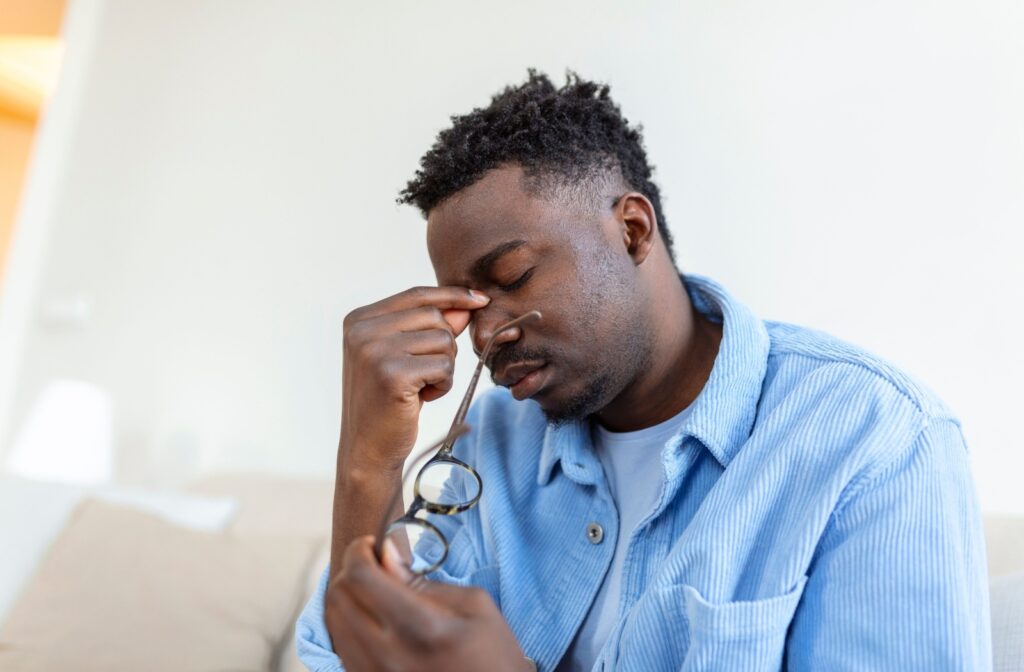 A person holding their glasses after removing them so they could rub their dry eyes